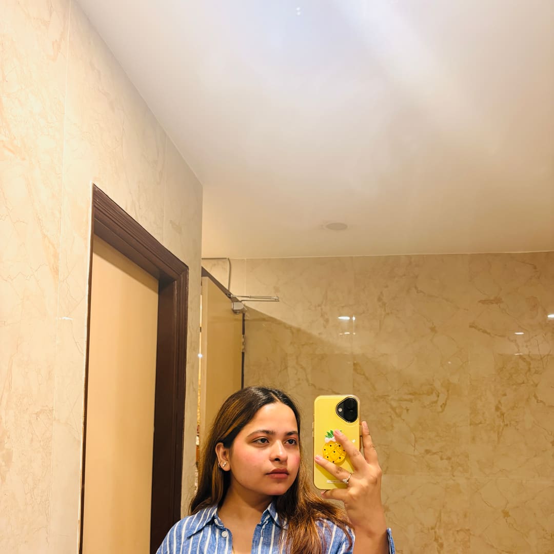 Soumya Singh in a blue and white striped shirt, photographed in a marble-lined corridor