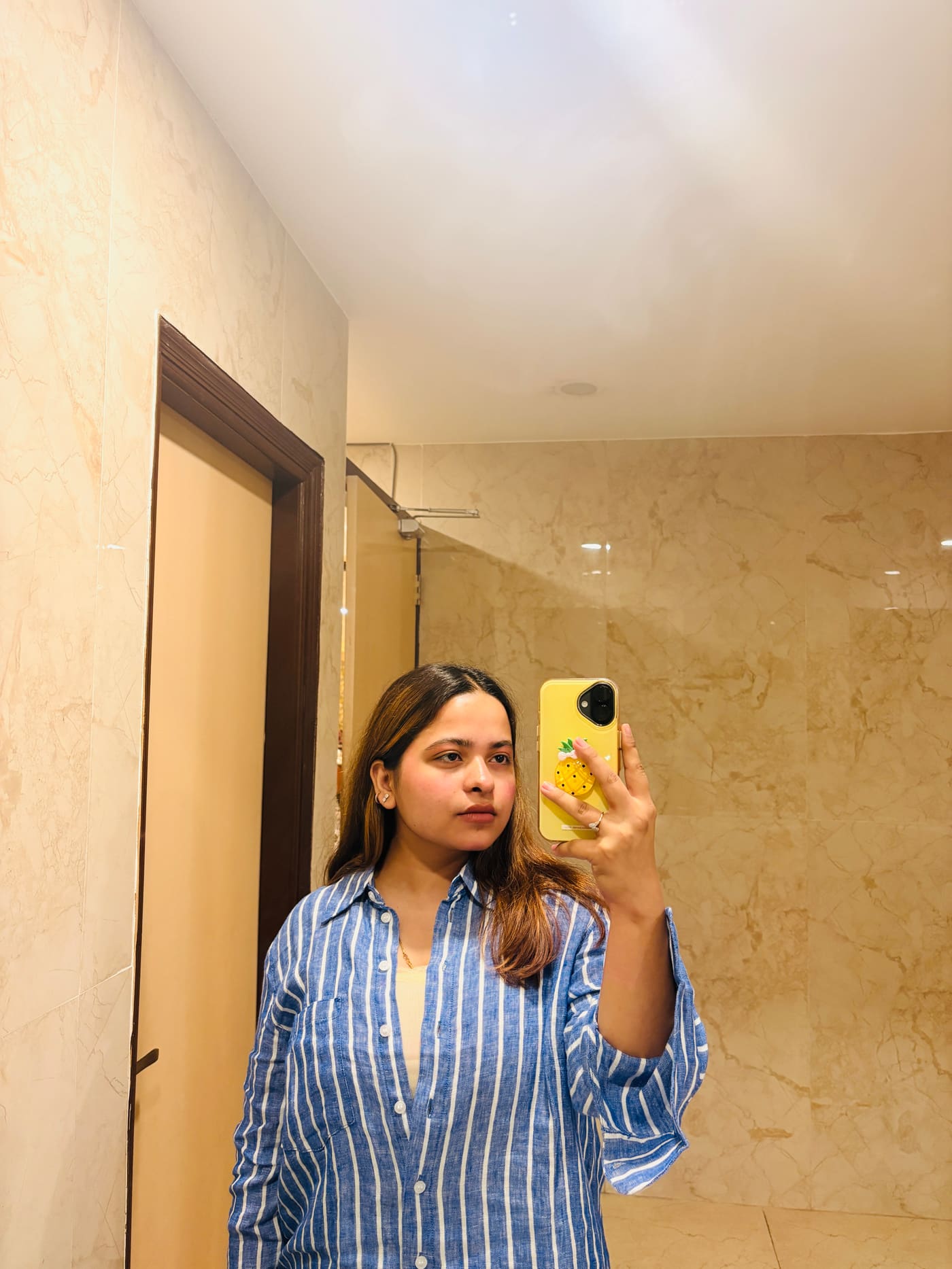 Soumya Singh in a blue and white striped shirt, photographed in a marble-lined corridor