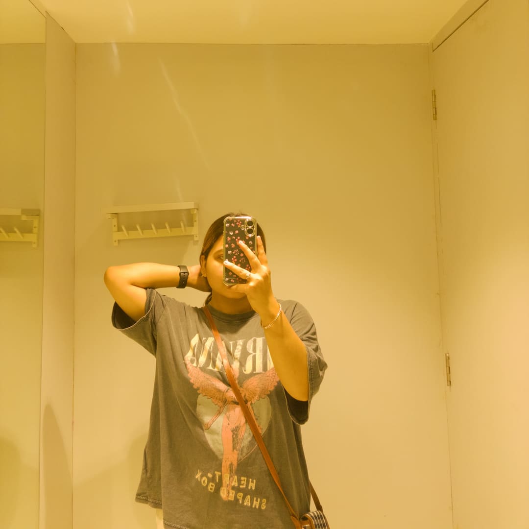 Soumya Singh in an oversized graphic tee, photographed in warm tungsten light